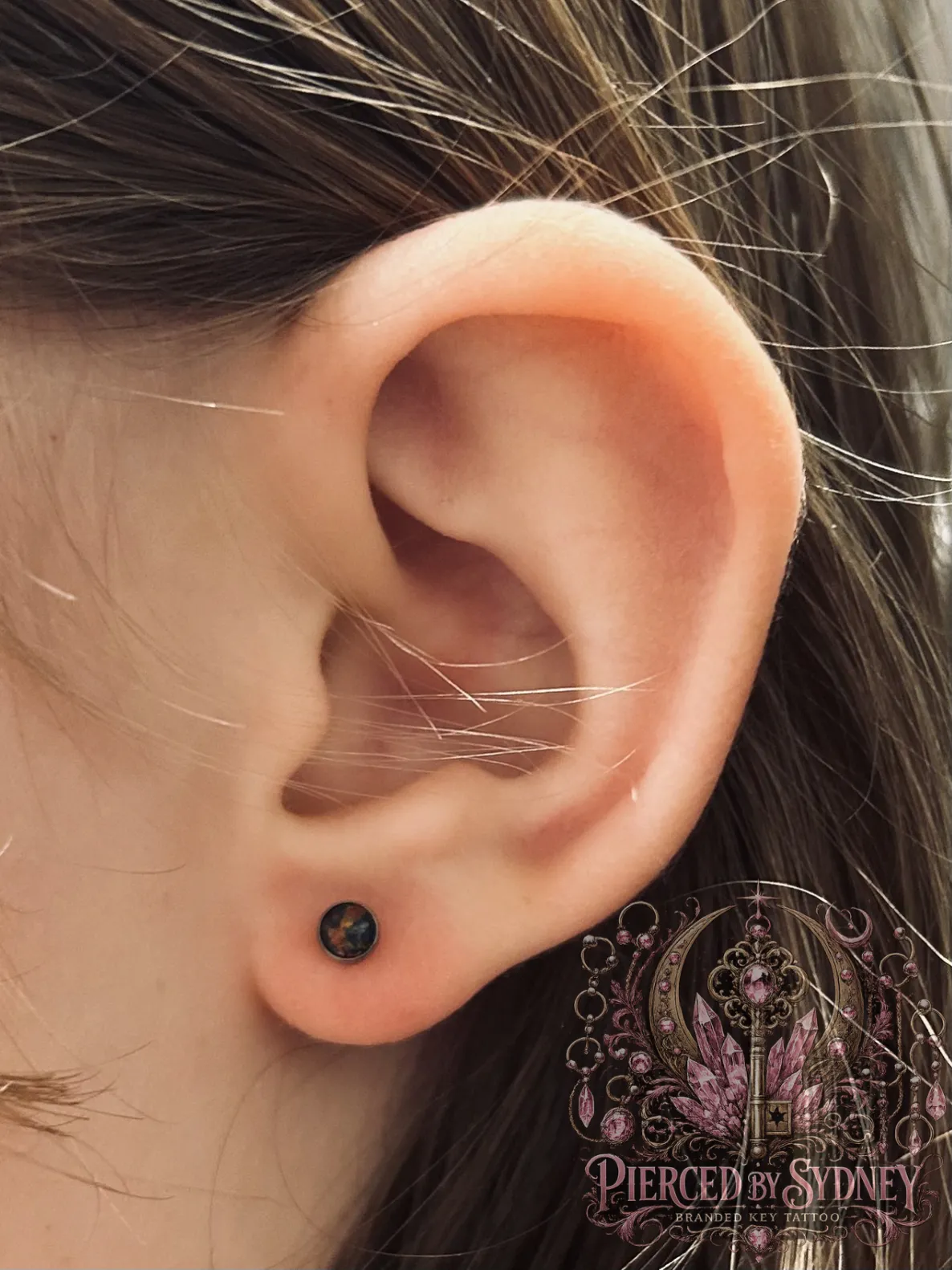 Lobe piercing with black jewelry by Sydney