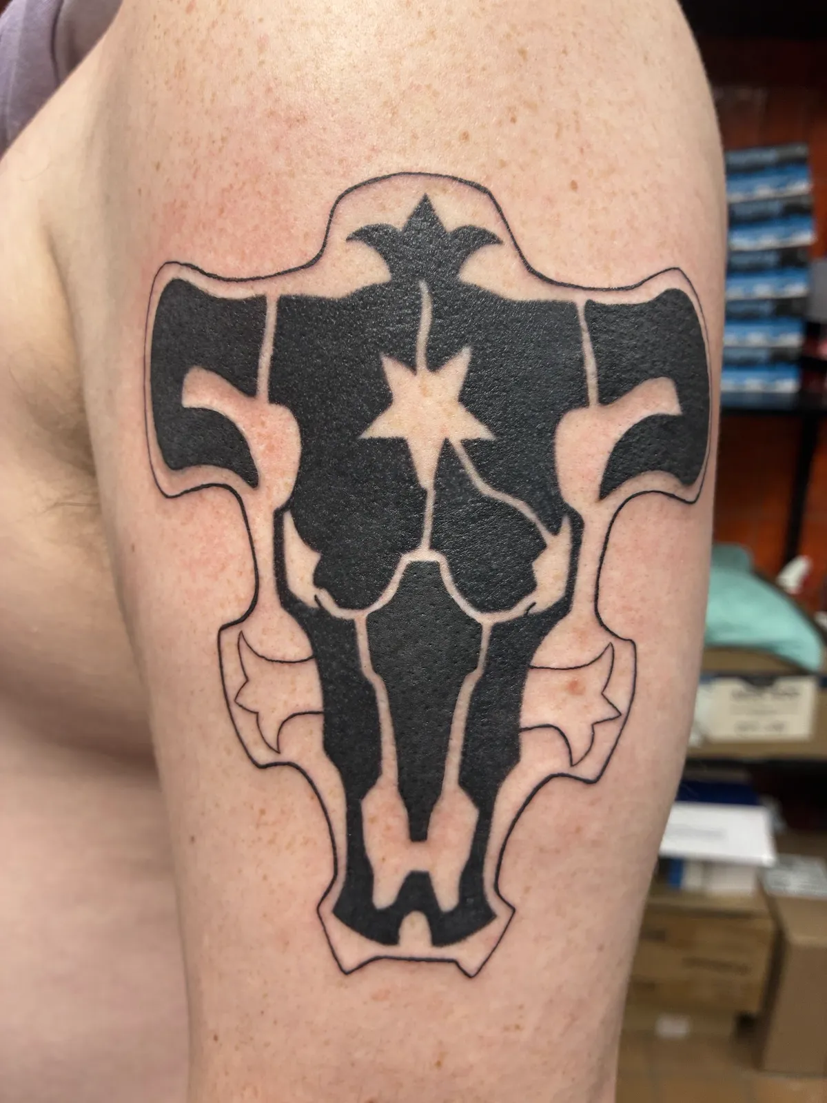 Bold black emblem shoulder tattoo by Sav