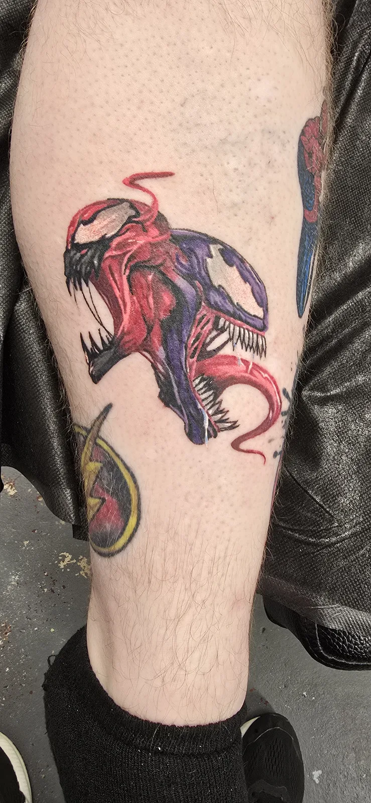 Red and black creature leg tattoo by Joshua Key